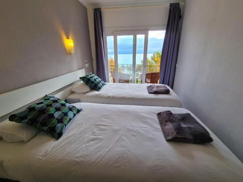 萨科马Amena Mar Hotel的配有窗户的酒店客房内的两张床