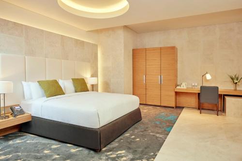 马斯喀特Aerotel Muscat - Airport Transit Hotel的一间卧室配有一张大床、一张桌子和一张书桌