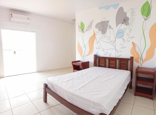 普拉杜Casa para temporada c/ ar condicionado, próximo da praia e do Beco das Garrafas的一间卧室设有一张床和鲜花墙