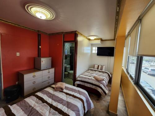 Alto HospicioHotel La Pampa的红色墙壁客房的两张床