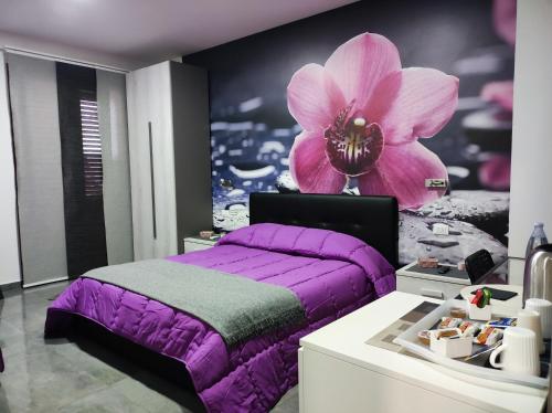 尼科洛西B&B La Grotta的一间卧室配有紫色的床,墙上挂着一朵花