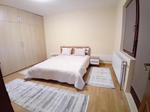 佩奇Pejë的卧室配有白色的床和白色地毯。