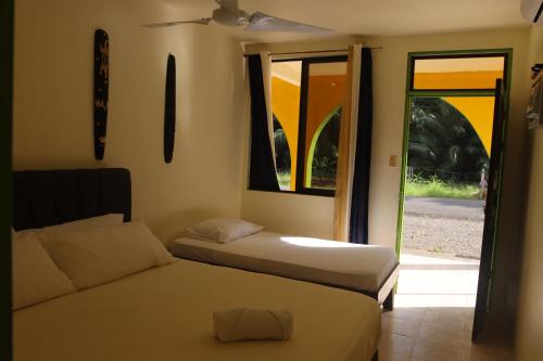 曼萨尼约Cool & Calm Hotel的一间卧室设有两张床、一个窗口和一扇门
