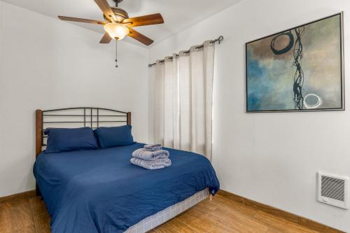 弗拉格斯塔夫Greenlaw Studio in the Pines!的一间卧室配有一张带蓝色床单的床和吊扇。