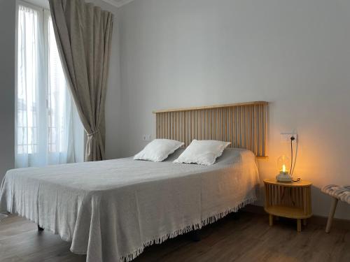 瓦伦西亚Maison Sereine的一间卧室配有一张带白色床单的床和一扇窗户。