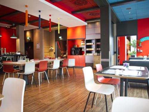 科隆科隆展览中心宜必思酒店的餐厅设有白色的桌椅和红色的墙壁