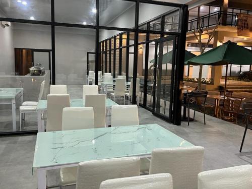 TjolomaduGenio Syariah Hotel Solo的一间设有白色椅子和桌子的用餐室以及窗户。