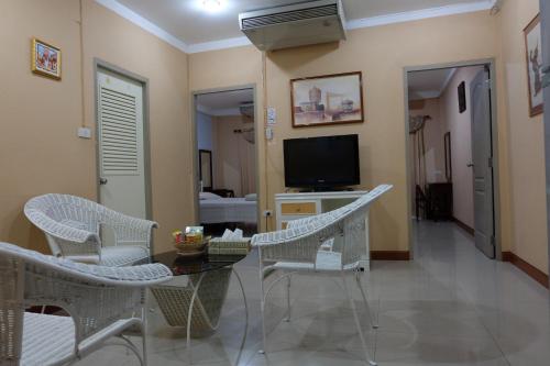 曼谷PR之地酒店的客厅配有桌椅和电视。