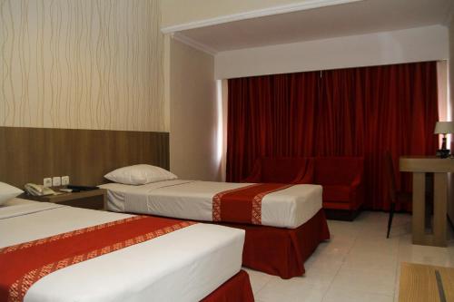 日惹University Club (UC) Hotel UGM的酒店客房,配有两张床和椅子