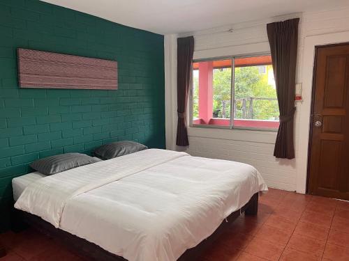 清迈红砖旅舍的一间卧室设有一张带床铺的绿色墙壁