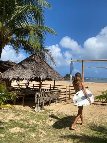 BarasPacific Surf and Yoga的一名年轻女孩在海滩上用冲浪板行走