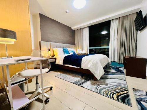 马尼拉Executive Queen 1BR Luxury Suite 10 - Pool, Wi-Fi的酒店客房配有一张床、一张书桌和一张书桌。