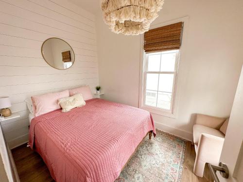 林垦The Haymarket Boho Bungalow的一间卧室配有粉红色的床和吊灯。
