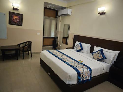 大诺伊达Blue Bell Hotel - Greater Noida的配有床、椅子和桌子的酒店客房