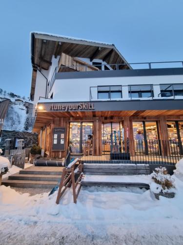 萨尔巴赫SKILL Mountain Lodge - Ski und Bike Hostel inklusive JOKER CARD的一座建筑物,上面有读饥肠 ⁇ 的标志,在雪中
