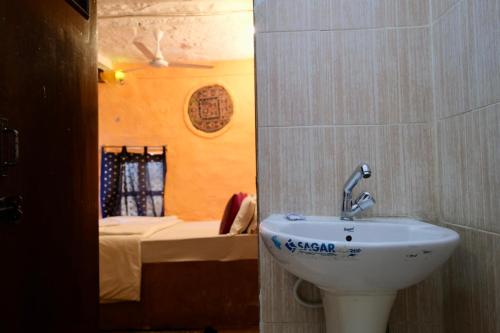 斋沙默尔Saffron Homestay的一间带水槽的浴室和一张位于客房内的床