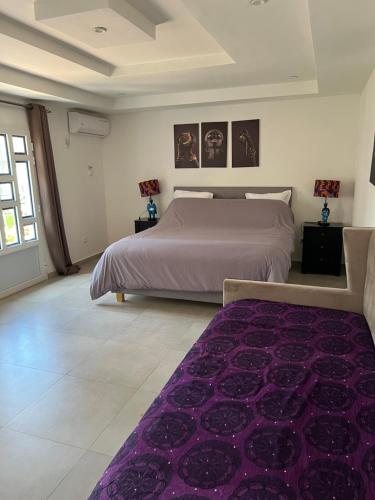 萨利波图尔Chez Lilie Maison d'hôtes à Saly的一间卧室配有一张大床和紫色地毯。