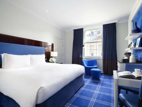 伦敦索菲特伦敦圣詹姆士酒店的酒店客房带一张大床和一把椅子
