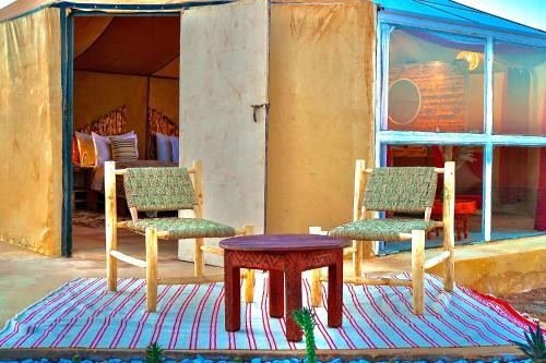 梅尔祖卡Sky View Camp的房屋前地毯上的两把椅子和一张桌子