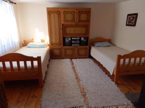 季米特洛夫格勒ETNO KOMPLEX NIKOLOV的一间卧室配有两张床、一个橱柜和一个地毯。