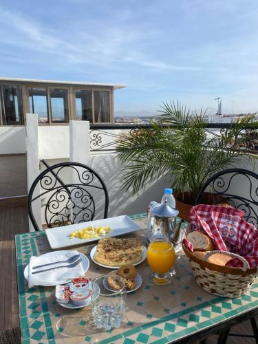 拉巴特Riad Jbara 2的阳台上的桌子上摆放着食物和橙汁