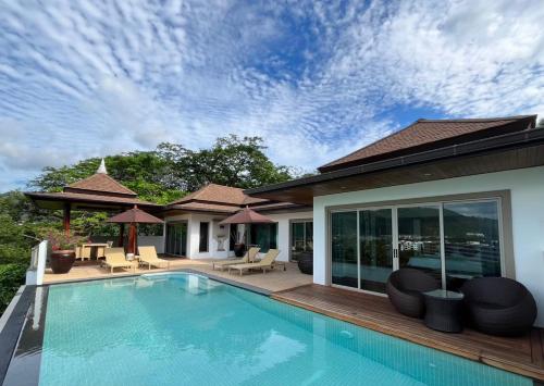 卡马拉海滩Villa Tantawan Resort - Private Pool Villas的一个带椅子的游泳池以及一座房子