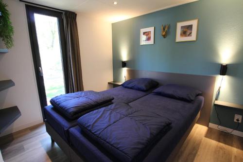 巴勒纳绍Tiny House的一间卧室配有一张带蓝色床单的大床