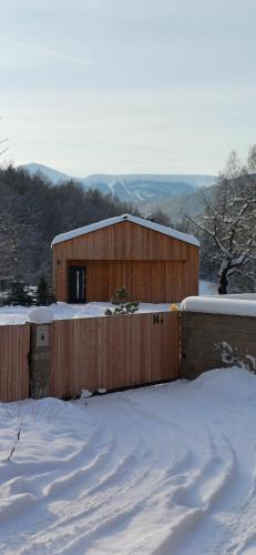 卡尔帕奇Górnolotnie koło Karpacza的雪中带围栏的木制建筑