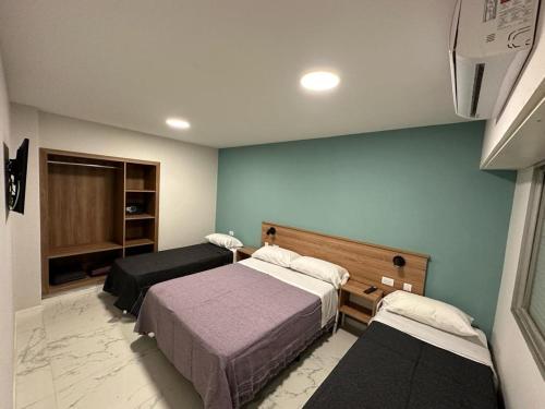 马德普拉塔Hotel Bermudas的一间设有两张床的卧室,位于蓝色墙壁的房间