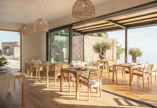 AyvacıkMomos Otel的餐厅设有木桌和椅子以及大窗户。