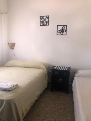 内科切阿Hotel CheMar的一间卧室配有两张床,墙上设有一张床头柜和两张照片