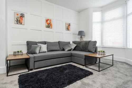 利物浦Harrow Lodge - Anfield Apartments的客厅配有灰色的沙发和2张桌子