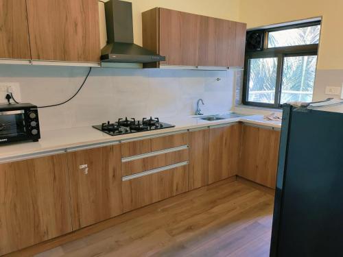 尼禄Luxury 2BHK Apartment Near Candolim的厨房配有木制橱柜和黑炉灶烤箱。