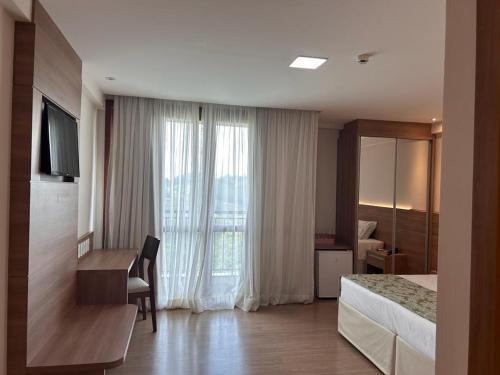 多明戈斯马丁斯Vista Azul Hotel的配有一张床、一张书桌和一扇窗户的酒店客房
