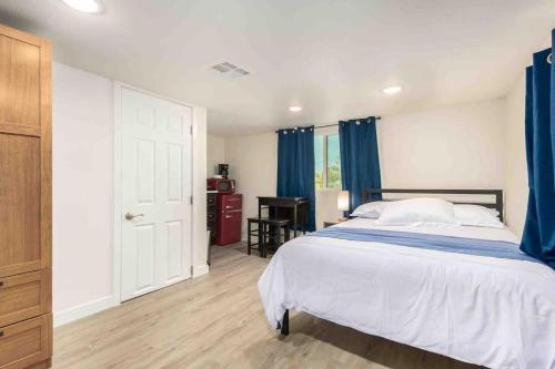 凤凰城Your Downtown Cozy Studio With Backyard Unit C的一间卧室配有一张带蓝色窗帘的床和一张书桌