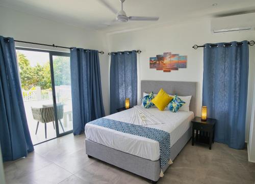 博瓦隆Sunset Haven Villa的一间卧室配有一张蓝色窗帘的床和一个阳台