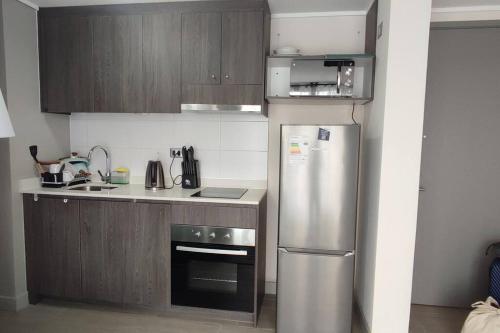 圣地亚哥Departamento nuevo y cómodo的厨房配有不锈钢冰箱和木制橱柜