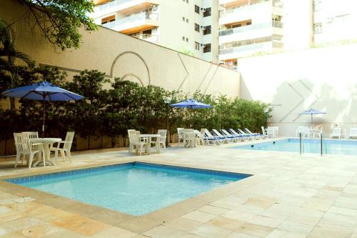 里约热内卢Apartamento aconchegante.的一个带桌椅和遮阳伞的游泳池