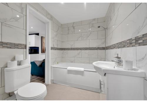 阿斯科特Modern Deluxe 3 Bedroom Flat的白色的浴室设有浴缸、卫生间和水槽。