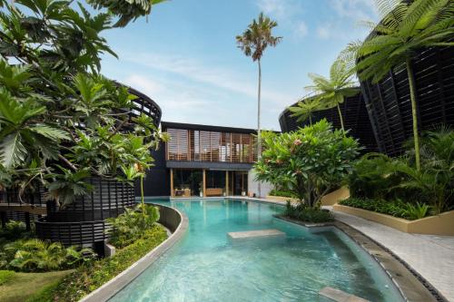 坎古Canggu Cabana Resort By Ini Vie Hospitality的一座树木繁茂的建筑中间的游泳池