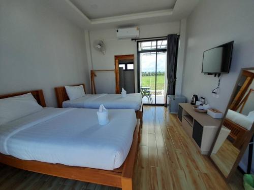 Ban Chalaengเดอนาปัว วิลล่า的酒店客房设有两张床和电视。