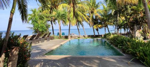 罗威那1000梦幻简易别墅酒店的一座棕榈树和海洋游泳池