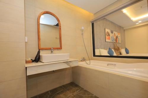 归仁FLC Quy Nhon Beach Apt的一间带水槽、浴缸和镜子的浴室