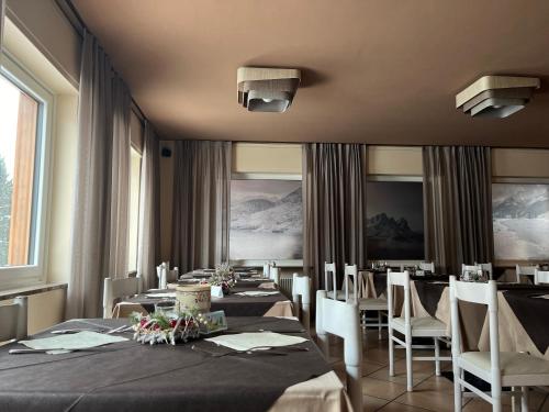 坎皮泰洛迪法萨Hotel Rododendro Val di Fassa的用餐室配有长桌子和椅子