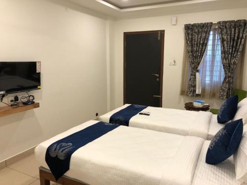 班加罗尔Hotel Amulya Regency的配有电视的酒店客房内的两张床