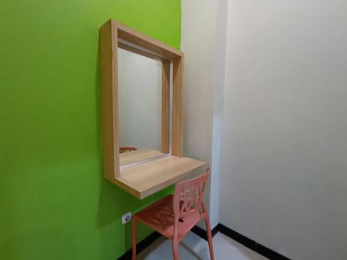 日惹The Cabin Hotel Ngupasan的浴室设有镜子和粉红色的椅子