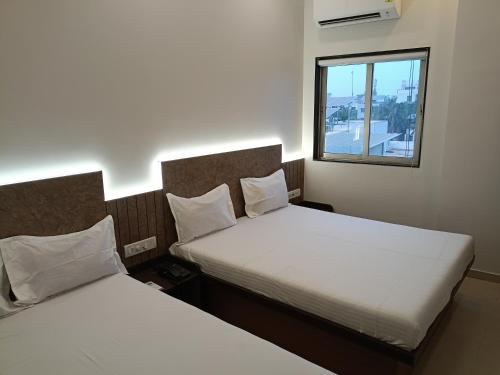 苏拉特Hotel Ritz Vesu - Hotels in Vesu, Surat的小型客房 - 带2张床和窗户