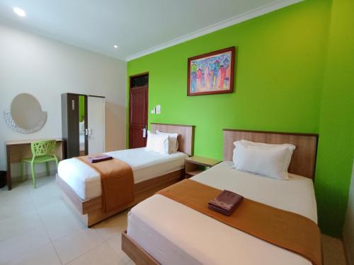 日惹The Cabin Hotel Ngupasan的一间设有两张床和绿色墙壁的客房