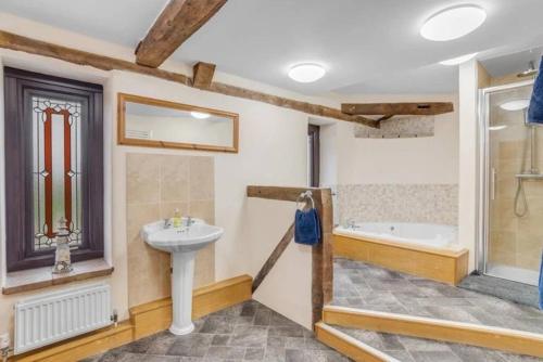 北沃尔舍姆amazing barn conversion with hot tub的浴室配有盥洗盆和浴缸。