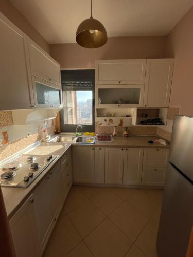 地拉那Easy Peasy - 9th floor view downtown的厨房配有白色橱柜、水槽和冰箱。